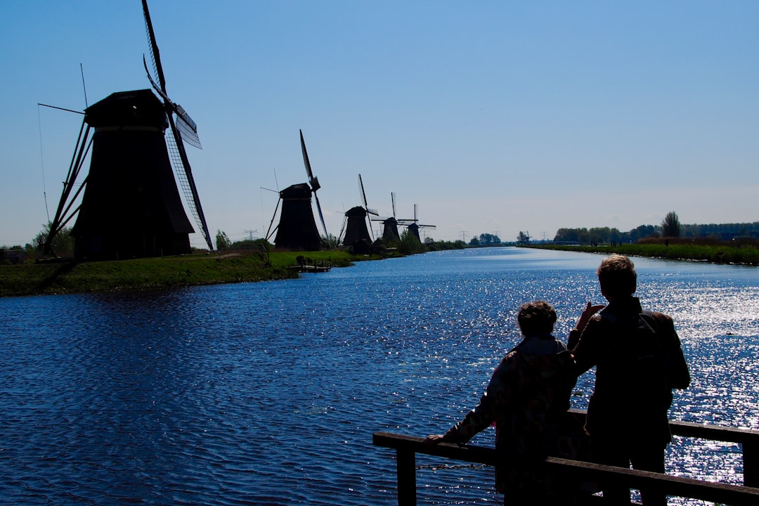 man and woman sitting on bench near body of water during daytime